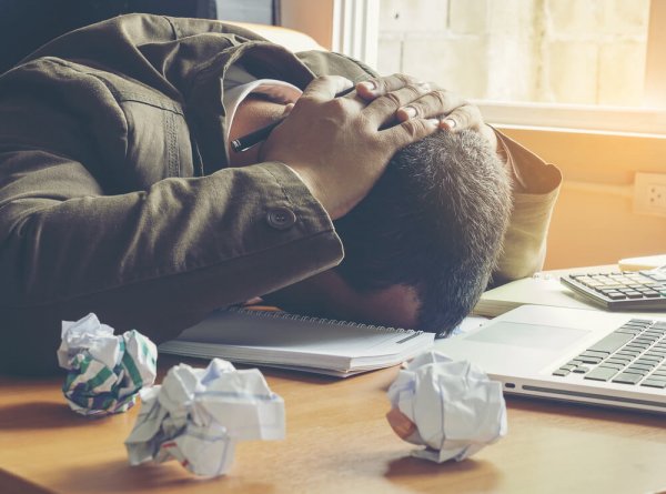 frustrated man at a desk with crumpled up paper
