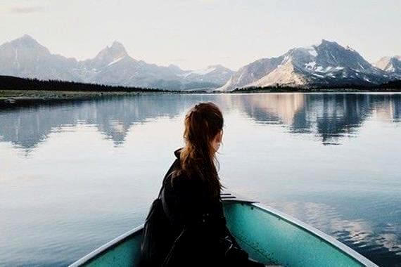 a woman in a rowboat on a mountain lake thinking about what makes you happy