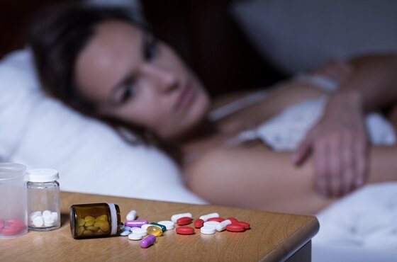 a woman looking at insomnia medication on the night stand
