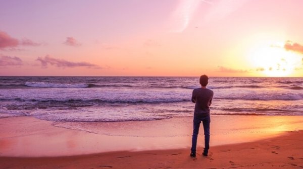 a lone man looking at the ocean with his arms crossed