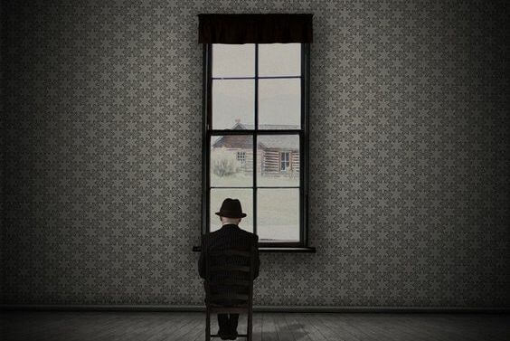A man is looking out the window to a winter landscape.