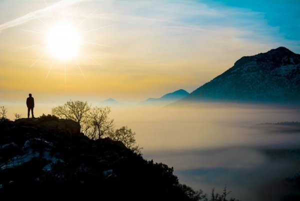 a man on a mountaintop looking at the fog