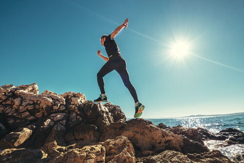 a runner leaping up a hill by the water