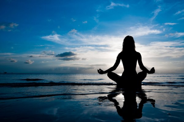 a woman practicing meditation and mindfulness on the beach