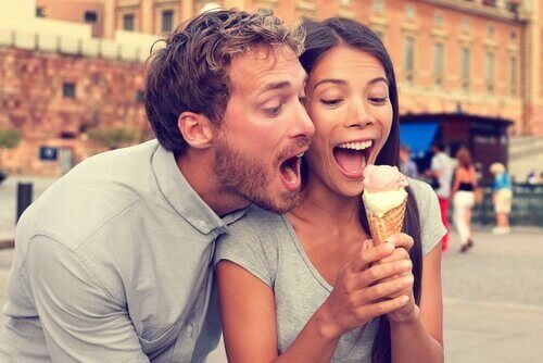A happy couple eating an ice cream cone.