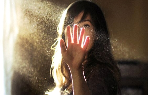 a woman putting her hand in a ray of sunlight