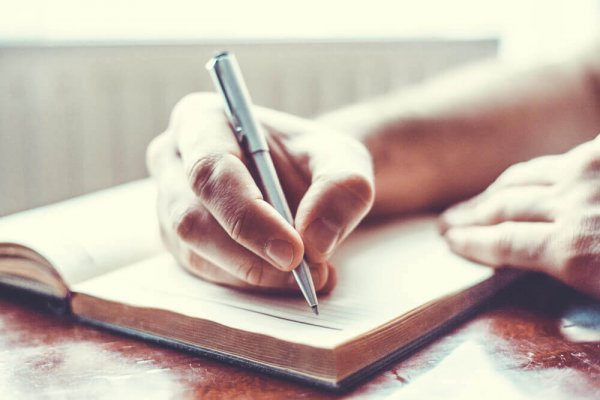 a person writing in a diary with a pen