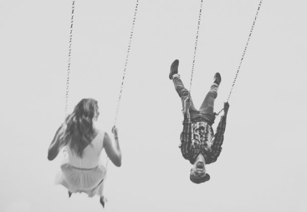 Happy people swinging on swings up high.