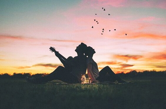 a couple, the man playing a guitar