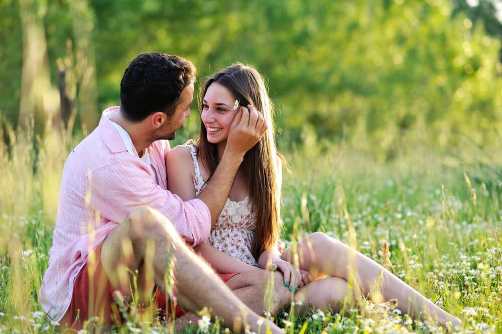 A couple in love is sitting together in the grass.