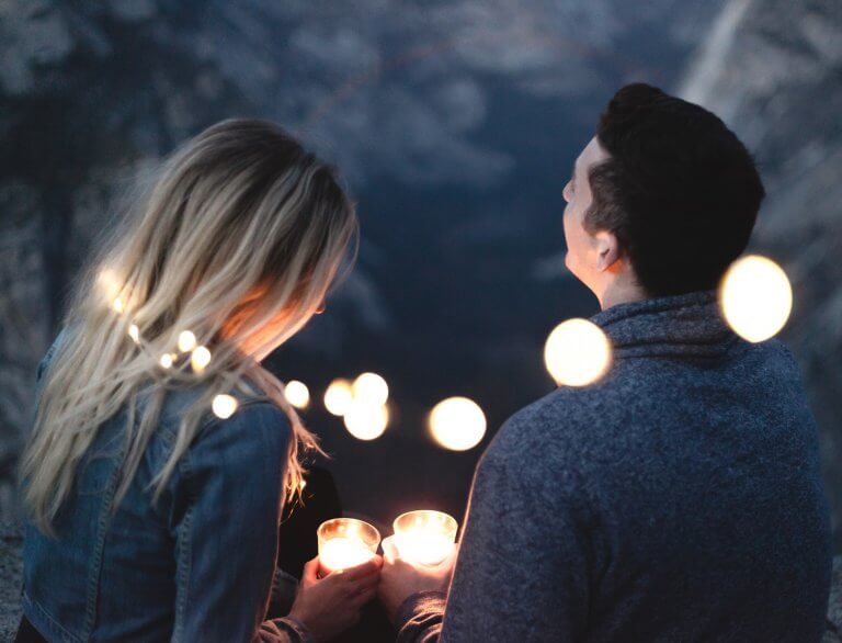 A couple is surrounded by lights and holding candles.