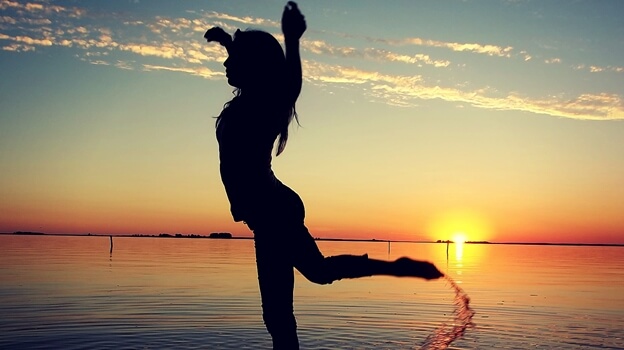 a girl doing a dance on the beach