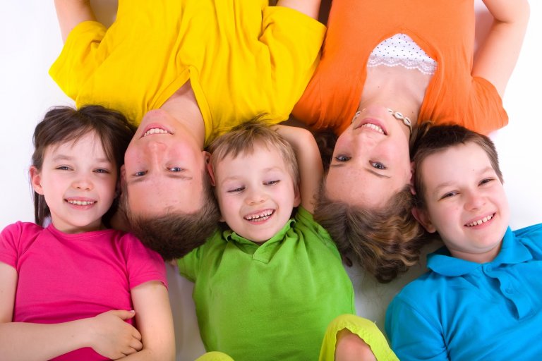Five happy children laying side by side.