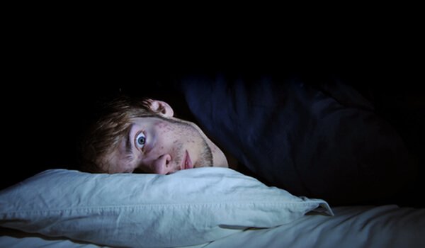 a man lying in bed with eyes wide open