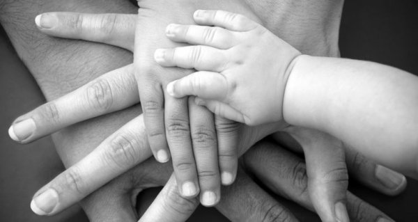 a baby's hand on top of other hands