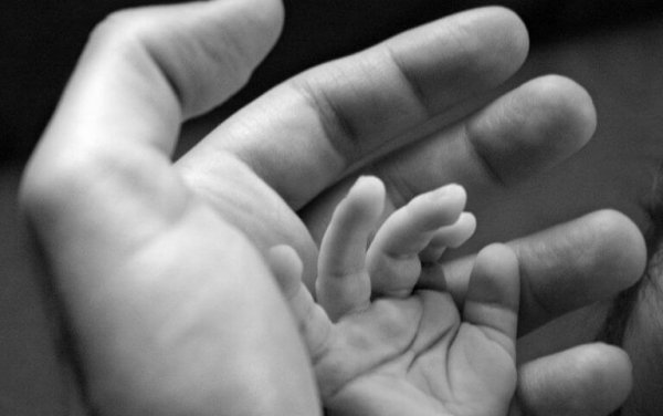 A baby's hand inside an adult hand.