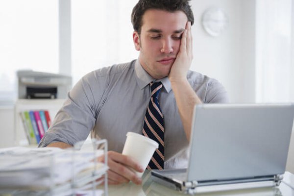 overworked, stressed office worker at his laptop with coffee