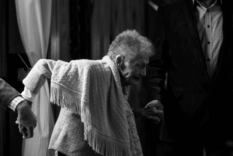 an elderly woman being supported by two men