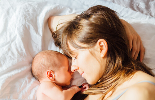 a mom and her child cuddling and sleeping in bed