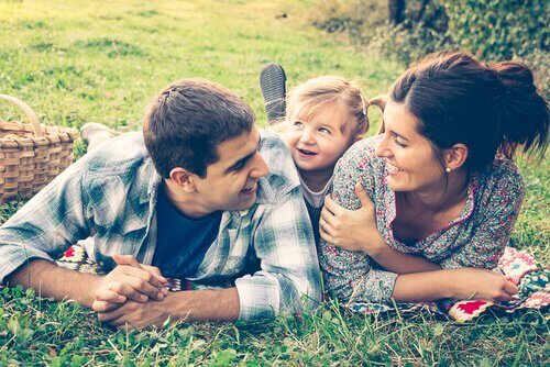 Two parents are with their small daughter in the grass.