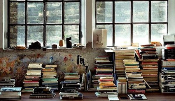 piles of books in a messy room that needs organizing