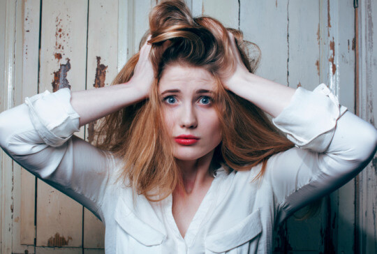 Red-haired girl with messy hair worrying.