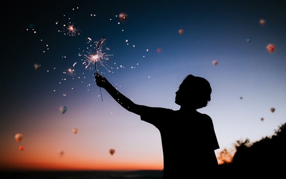 a silhouette with a sparkler at sunset