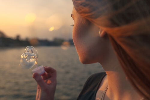 a woman blowing a bubble at sunset on the sea