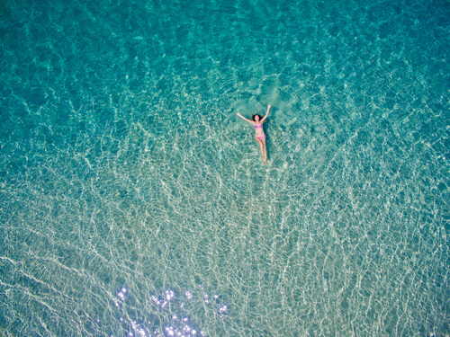 A paradise: a woman floating on a beautiful blue ocean.