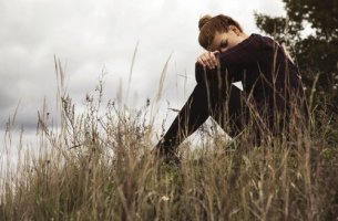 Woman is sitting in a field feeling guilt