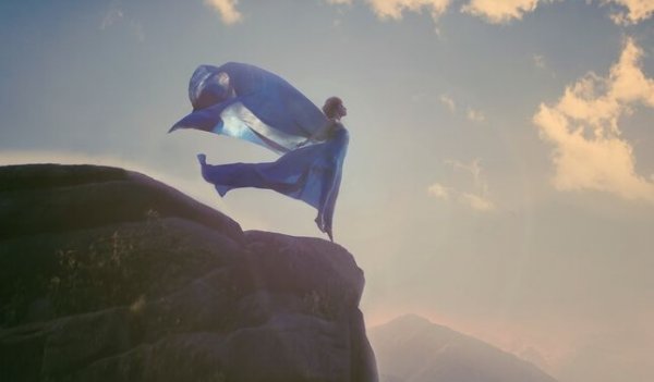 a woman with flowing clothes at the edge of a cliff
