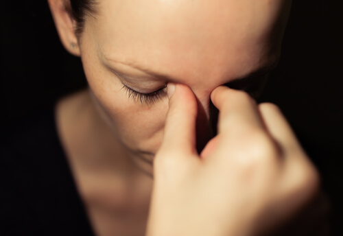 An upset woman pinching the bridge of her nose.