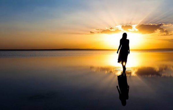 silhouette of a woman on water in front of the sunset
