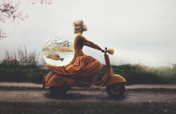 A woman on a motorbike with a fishbowl.