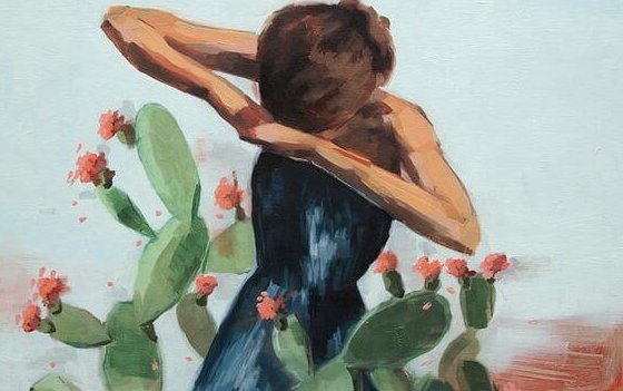 A girl is standing among cacti.