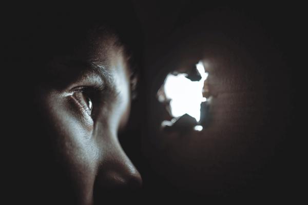 a boy looking out of a hole in a box, experiencing separation anxiety