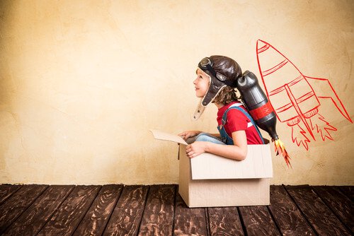 A boy is sitting in a box pretending that its a rocket.