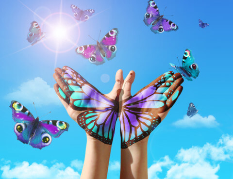 A colorful butterfly overlapping someones hands.