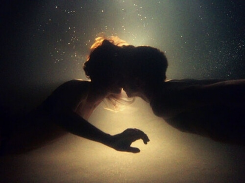 Two people kissing underwater.