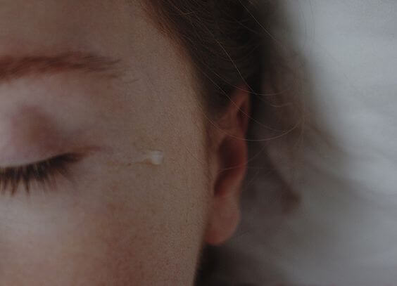 A tear running down the face of a crying woman.