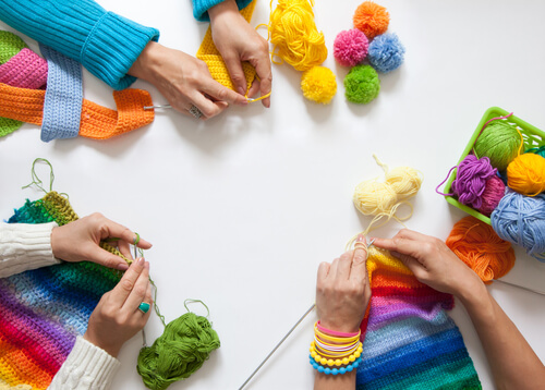 A group of friends knitting colorful crafts together.