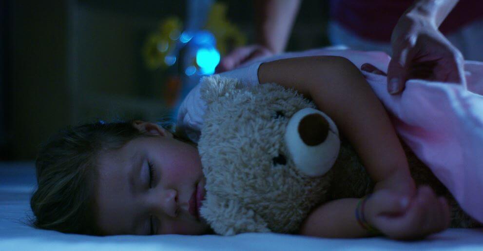 A little girl sleeping with her teddy bear.