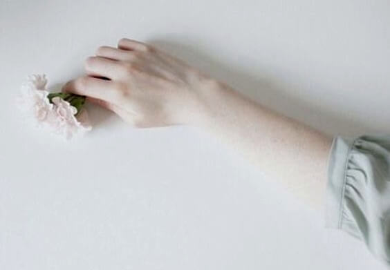 En blek arm som holder blomster.