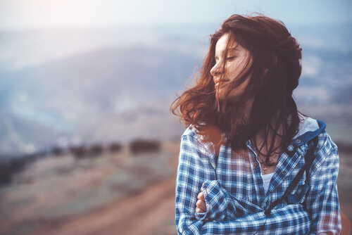 Happy girl hugging self.