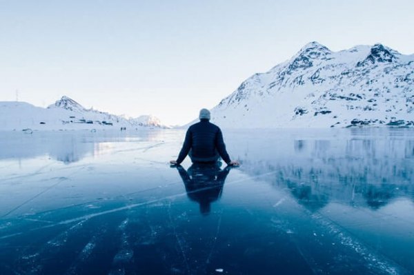 A man sitting on ice in the mountains.