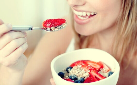 A woman eating oatmeal with berries to increase her serotonin.