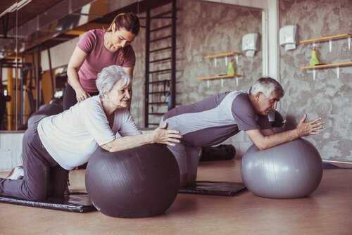 Older people exercising on yoga balls with a trainer.
