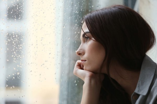 A sad woman gazing out a rainy window.