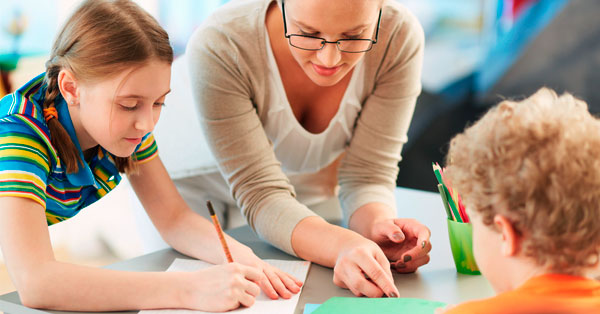 A teacher helping two students.