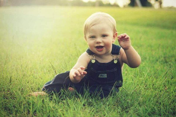 A baby's development: a baby playing in the grass.